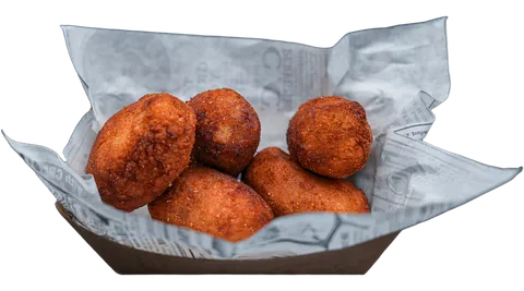Cinco croquetes artesanais dourados servidos em barquete.
