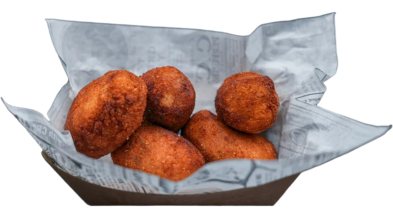 Cinco croquetes artesanais dourados servidos em barquete.